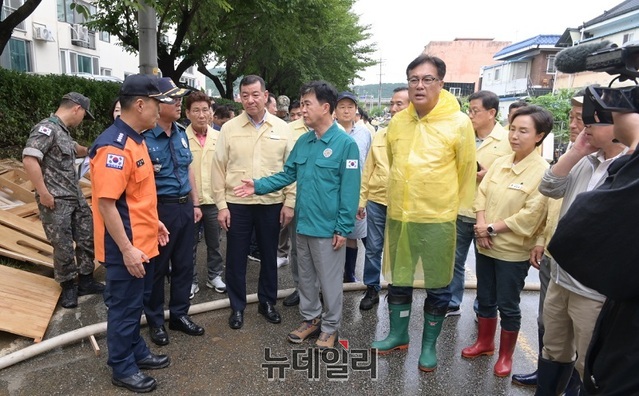 ▲ 최원철 충남 공주시장(앞줄 왼쪽 세번째)이 지난 16일 김태흠 충남지사와 정진석 국회의원과 함께 옥룡동 침수 피해 입은 금강빌라 등 응급 복구현장 방문했다. 하지만 일부 주민들은 구두를 신고 침수 현장을 찾은 최 시장의 어설픈 모습과 행동을 보고 구설과 비판이 이어졌다.ⓒ이길표 기자