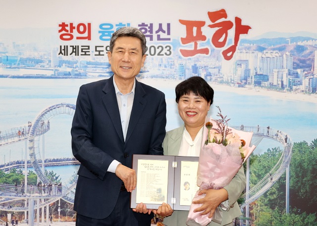 ▲ 박주희 포항문화재단 사무국장(우측)이 31일 명예퇴직하며 이강덕 포항시장에게 공로패를 수여받고 있다.ⓒ포항시