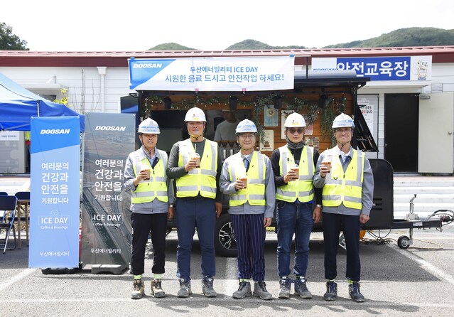 ▲ 경남 합천군에 위치한 함양-창녕간 고속도로 건설현장에서 두산에너빌리티와 협력사 직원들이 커피차 앞에서 기념촬영을 하고 있다. ⓒ두산에너빌리티