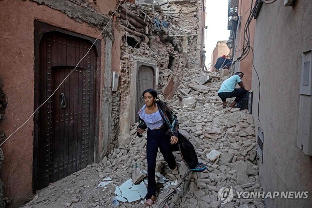 ▲ 강진이 발생한 모로코 마라케시에서 무너진 건물 사이로 걸어가는 여성. ⓒAFP 연합뉴스