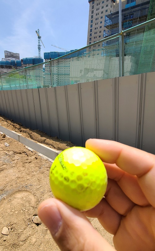 ▲ 최근 세종필드GC 골프장 이용자가 친 골프공이 인근 아파트 공사현장으로 떨어져 입주 예정자가 골프공을 보이고 있다.ⓒ세종시의회