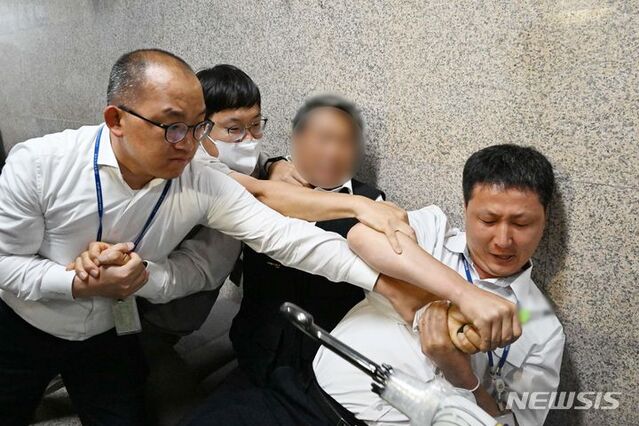 ▲ 이재명 더불어민주당 대표의 단식 16일째인 15일 오후 서울 여의도 국회 본청 내 민주당 대표실 앞에서 김모(73)씨가 혈서 작성을 위해 커터칼을 들자 국회 경비대들이 저지하고 있다. ⓒ뉴시스