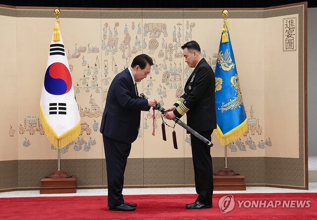 ▲ 윤석열 대통령이 30일 서울 용산 대통령실 청사에서 열린 장성 진급·보직 신고 및 삼정검 수치 수여식에서 대장으로 진급한 김명수 합동참모본부 의장 내정자의 삼정검에 수치를 직접 매어주고 있다.ⓒ연합뉴스