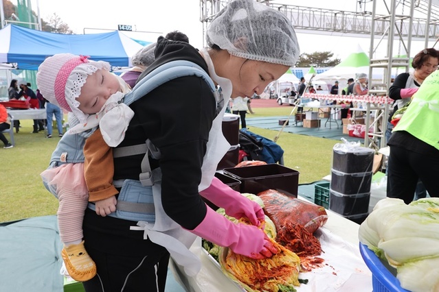 ▲ 아기를 업은 한 주부가 김장김치를 담고 있다.ⓒ충북도