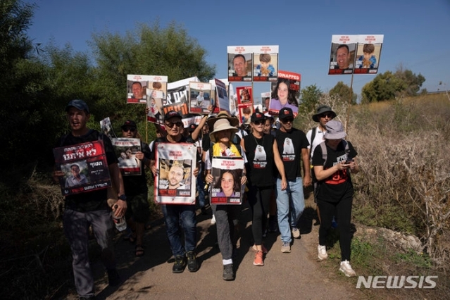 ▲ 피랍 이스라엘인들의 사진을 든 가족과 친구들이 16일(현지시각) 이스라엘 베이트 해스모니아 마을 인근을 행진하고 있다. 베냐민 네타냐후 총리는 인질 석방 협상 진전 관련 
