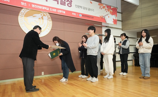 ▲ 사진은 시상식에서 장원으로 뽑힌 강미라 학생이 이영석 도서관장(왼쪽)으로부터 상을 받고 있다.ⓒ영진전문대