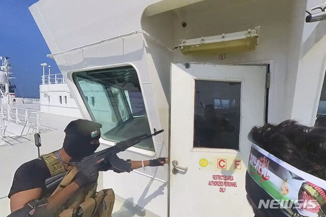 ▲ 예멘 후티 반군 측이 공개한 영상 사진에 지난 19일(현지시각) 자동소총으로 무장한 후티군 병사가 화물선 갤럭시 리더호에 승선해 조타실로 접근하고 있다. 후티 반군은 이스라엘 기업이 보유한 선박을 모두 나포하겠다고 위협한 뒤 예멘 연안 홍해에서 화물선을 나포했다. ⓒ뉴시스
