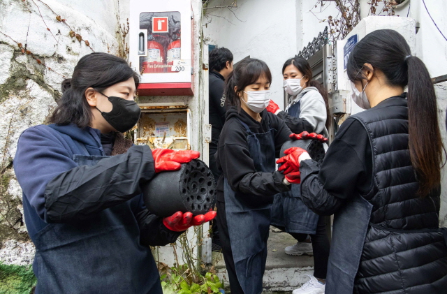 ▲ DL이앤씨 임직원 가족들이 서울 서대문구 홍제동 개미마을에서 연탄을 나르고 있다. ⓒDL이앤씨