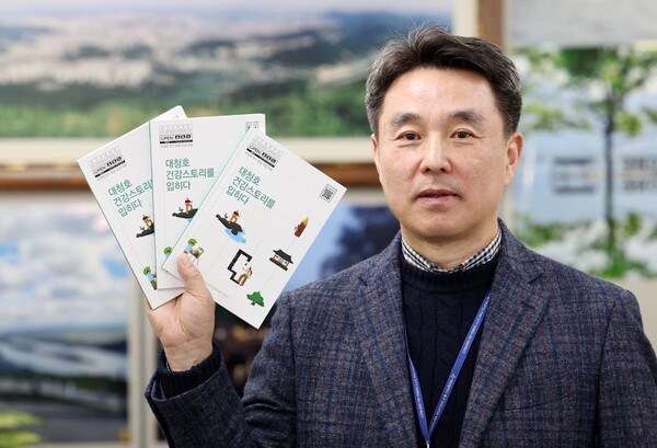 ▲ 이규승 동구보건소 전문경력관이 ‘대청호 건강스토리를 입히다’ 책자를 들고 기념 촬영을 하고 있다.ⓒ동구