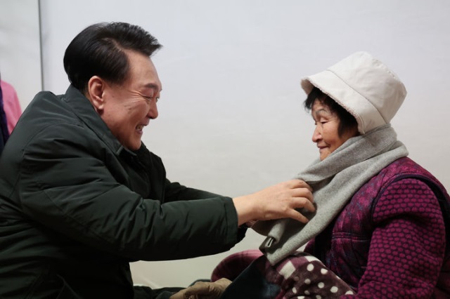 ▲ 윤석열 대통령이 지난해 12월21일 한파 시기 서울 중랑구 한 다세대 주택을 찾아 어르신에게 난방용품을 전달하며 목도리를 둘러드리고 있다.ⓒ대통령실 제공