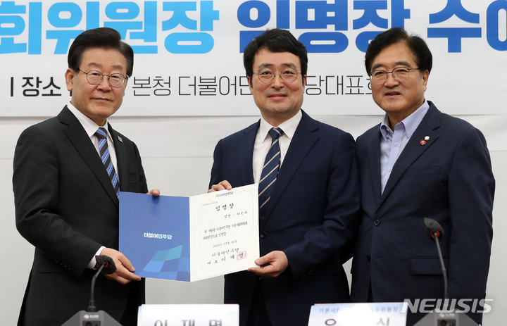 ▲ 더불어민주당 기본사회위원회 위원장인 이재명 대표가 지난해 6월, 서울 여의도 국회에서 열린 기본사회위원회 광역 기본사회위원장 임명장 수여식에서 이헌욱 부위원장에게 임명장을 수여한 후 기념촬영을 하고 있다. 오른쪽은 수석부위원장인 우원식 의원. ⓒ뉴시스