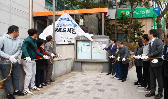 ▲ 기흥구 상갈동 행정복지센터 1층 야외 부스에서 열린 스마트도서관 11호점 개관식에서 이상일 용인특례시장(오른쪽에서 일곱번째) 등 참석자들이 제막식을 하고 있다. ⓒ용인시 제공