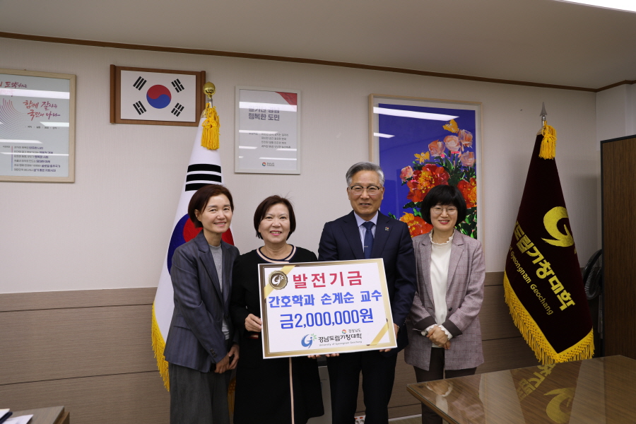 ▲ 손계순 교수가 김재구 총장에게 발전기금을 전달하고 참석자들과 환하게 웃고 있다. ⓒ도립거창대 제공