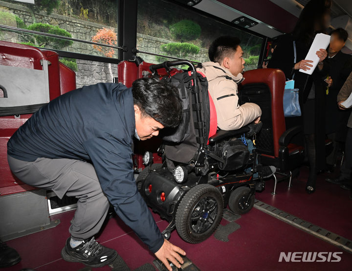 ▲ 복지관 관계자가 지난해 11월29일 휠체어 탑승 고정 장치 이용법을 시연하고 있다. ⓒ뉴시스