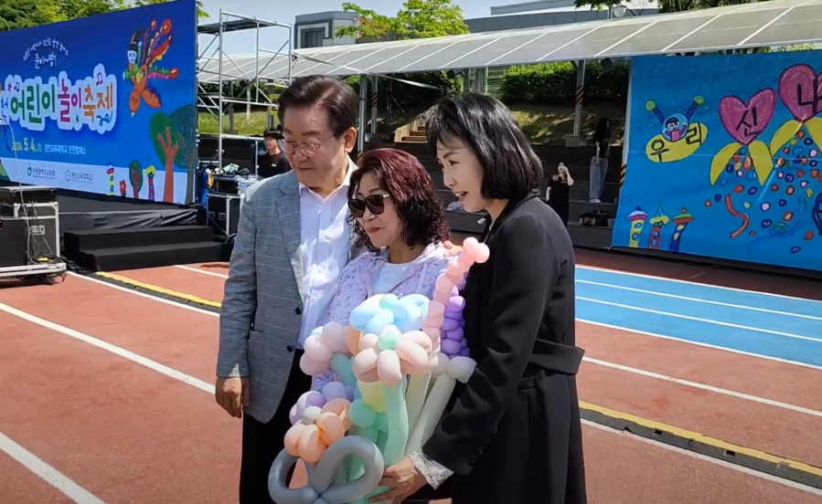 ▲ 이재명 더불어민주당 대표의 배우자 김혜경씨가 이 대표와 어린이날 행사에 참석해 시민과 사진을 찍고 있다. ⓒ유튜브 이재명TV 캡처