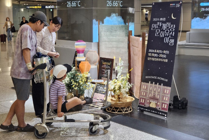 ▲ 인천국제공항 가족 이용객이 인천공항 여행자센터에 걸려 있는 '인천 개항장 문화유산 야행' 홍보 포스터를 보고 있다. ⓒ인천관광공사 제공