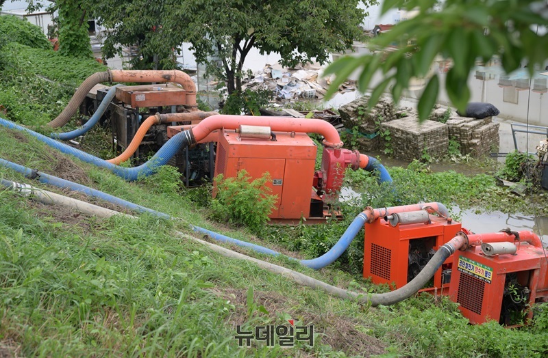 ▲ 논산시 공무원들이 집중 호우로 물에 잠긴 주택에서 펌프로 배수작업을 하고 있다.ⓒ이길표 기자