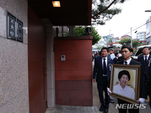 ▲ 이희호 여사의 영정이 2019년 6월 14일 오전 서울 동교동사저 대문 옆에 나란히 걸린 '김대중·이희호' 문패 앞에 잠시 멈춰서 있다. ⓒ뉴시스