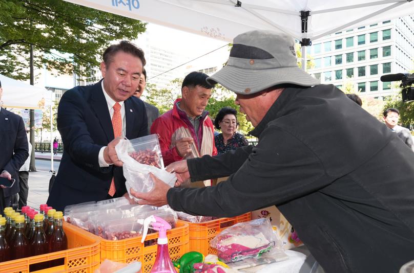 ▲ 유재훈 예금보험공사 사장이 2일 본사 앞에서 열린 ‘행복예감 직거래장터’에 방문해 땅콩을 구매하고 있다. ⓒ예금보험공사 제공.