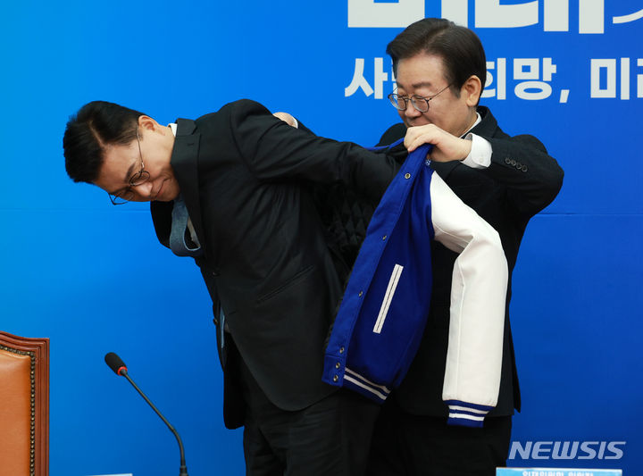 ▲ 이재명 더불어민주당 대표가 2월 7일 서울 여의도 국회에서 열린 15·16·17차 인재영입식에서 신용한 전 서원대 석좌교수에게 점퍼를 선물하고 있다. ⓒ뉴시스