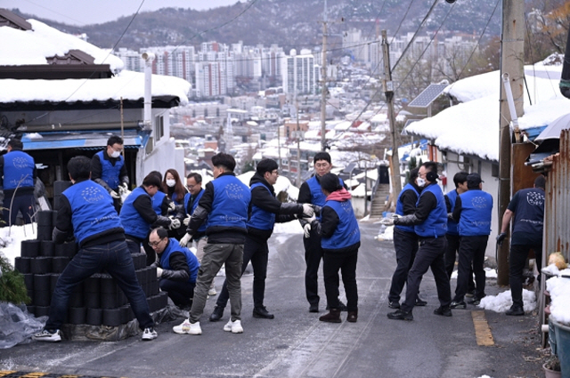 ▲ 동문건설 임직원 등이 지난 11월 29일 홍제동 개미마을에서 취약계층을 위한 연탄을 직접 배달하고 있다.ⓒ동문건설