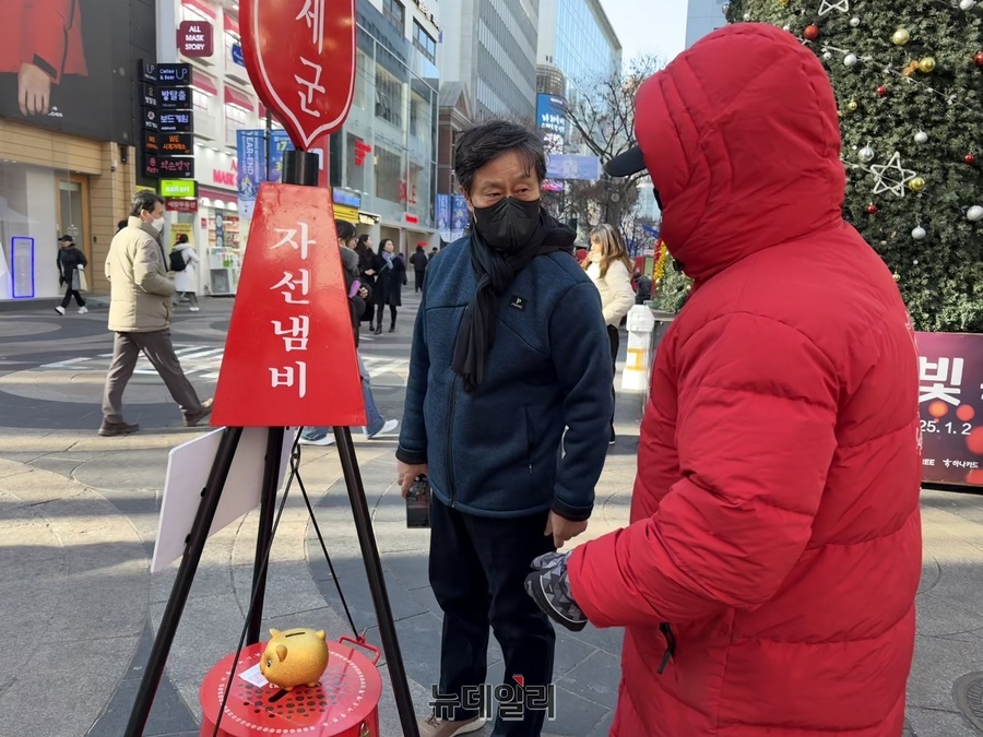 ▲ 크리스마스 이브인 24일 서울 중구 명동거리에서 한 남성이 구세군 자선냄비에 돼지 저금통을 기부하고 있다. 2024.12.24. ⓒ정혜영 기자