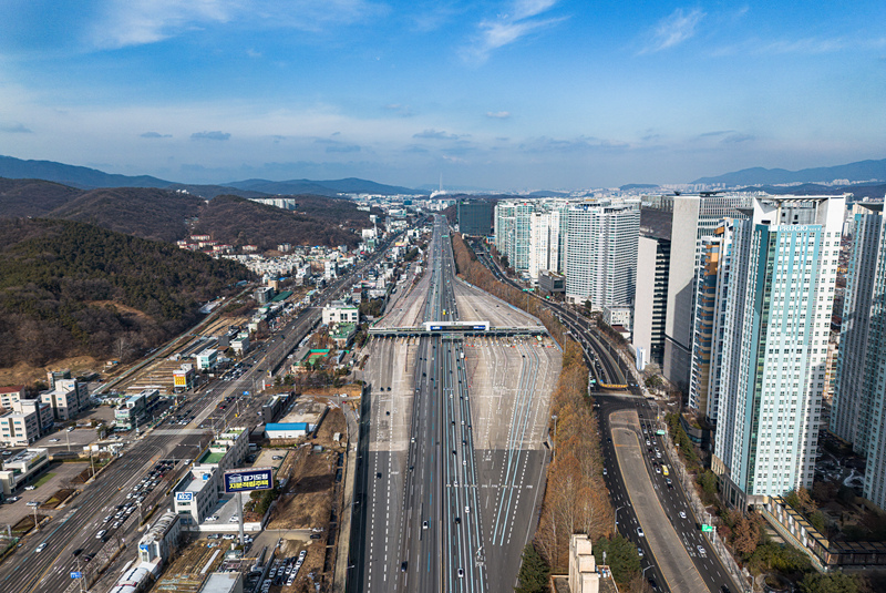 ▲ 대한민국의 고도 발전을 상징하는 '국토의 대동맥' 경부고속도로에 화물차와 고속버스 등 차량들이 통행하고 있다. 경기 성남시 서울톨게이트 입구에서 드론으로 본 모습. 멀리 롯데월드타워와 일대 서울도심이 관측된다. ⓒ경기 성남=서성진 기자