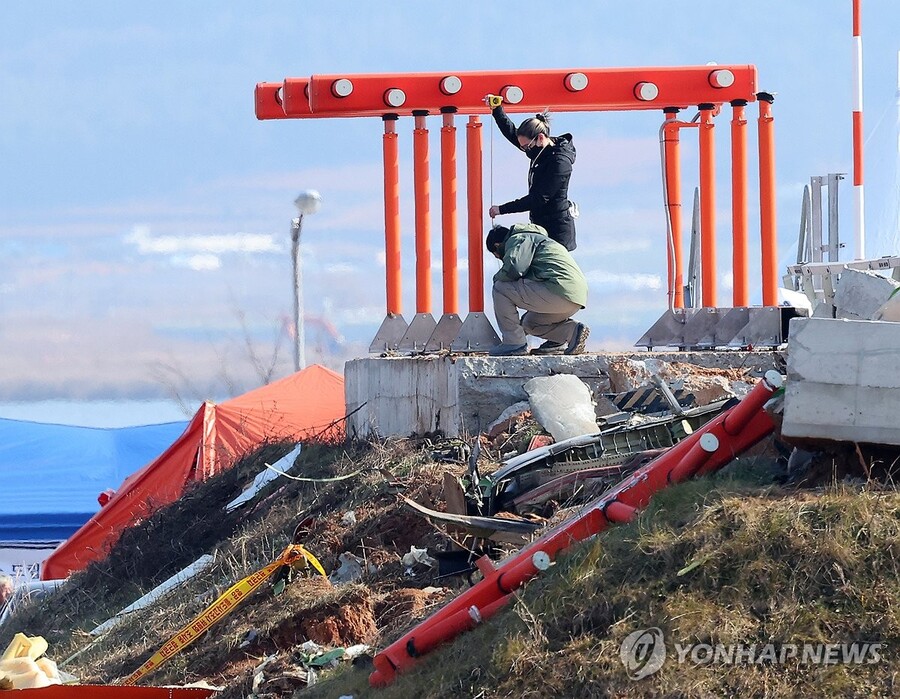 ▲ 2일 오전 전남 무안군 무안국제공항 제주항공 여객기 참사 현장에서 미국 합동조사팀 관계자로 보이는 외국 여성이 둔덕에 올라 로컬라이저 길이를 재고 있다. ⓒ연합뉴스