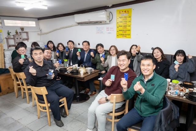 ▲ 수원시 공직자들이 수원 지역경제 활성화를 위해 골목상권을 이용한 뒤 수원페이를 들어보이고 있다. ⓒ수원시 제공