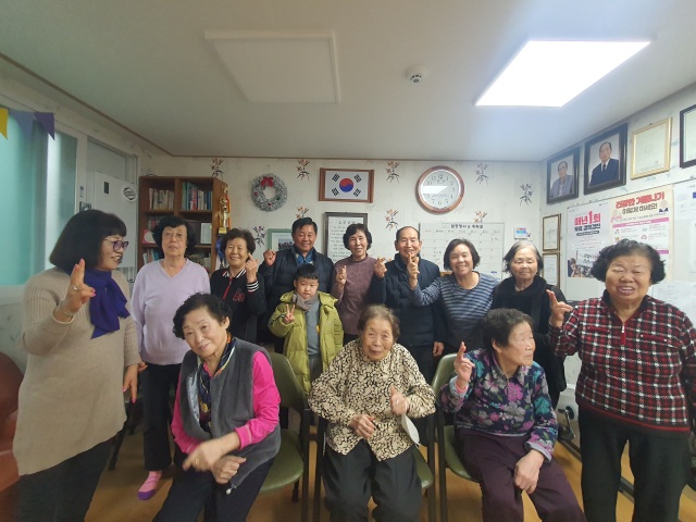 ▲ 수원 장다리 경로당 어르신들이 마을에서 3년 만에 초등학교에 입학하는 학생에게 장학금을 전달한 뒤 기념촬영을 하고 있다. ⓒ수원시 제공