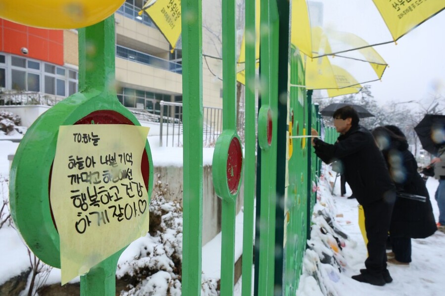 ▲ 대전 초등학생 김하늘 양 피살사건이 발생한 대전 서구의 한 초등학교 정문에서 12일 오전 학교 관계자가 추모객들이 놓고 간 꽃과 편지 위에 우산을 씌워주고 있다. ⓒ연합뉴스