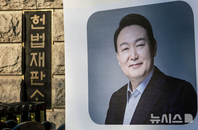 ▲ 윤석열 대통령의 탄핵심판 11차 변론이 열리는 25일 서울 종로구 헌법재판소 앞에서 한 지지자가 윤 대통령의 사진을 들고 있다. ⓒ뉴시스