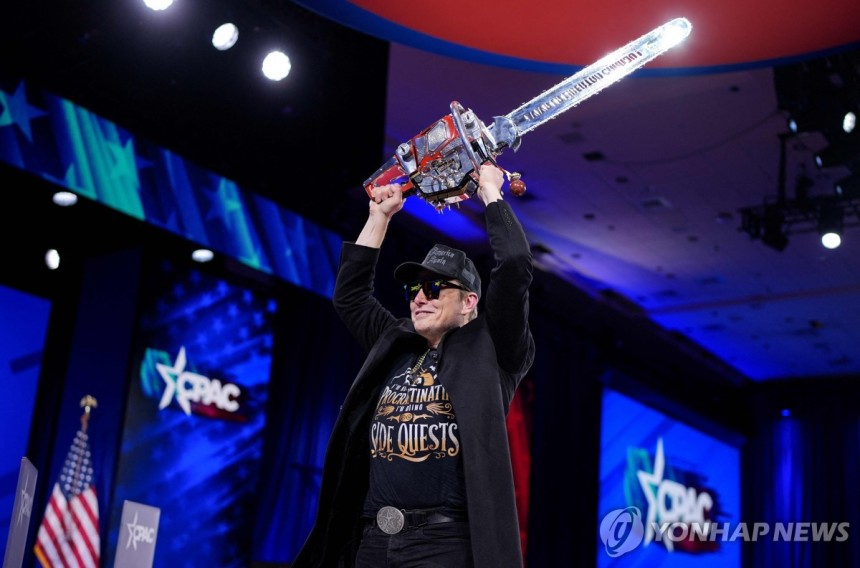 ▲ 전기톱을 치켜든 일론 머스크.ⓒ연합뉴스 제공.