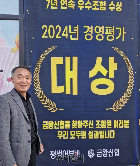 ▲ 반기태 이사장이 본점 앞에 게시된 대상 수상 현수막 앞에서 밝게 웃고 있다.ⓒ양승갑 기자