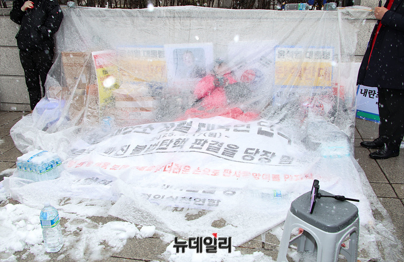 ▲ 전지영 국가정의실천연합 사무국장이 함박눈이 내리던 지난 4일 헌법재판소 앞에서 7일째 윤석열 대통령 탄핵 반대 농성을 벌이고 있다. 전 국장은 헌재 직원들이 그동안 '헌재는 개인 사유지'라고 주장하며 바람을 막기 위한 비닐조차 치지 못하게 했지만, 대통령 국민변호인단' 청년들이 '무제한 필리버스터 기자회견'을 시작하며 사람들이 몰리자 비닐 설치를 막지 않았다고 말했다. ⓒ서성진 기자