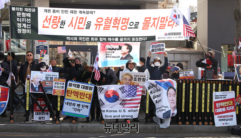 ▲ 13일 오후 서울 종로구 헌법재판소 정문 맞은편에서 윤석열 대통령 지지자들이 태극기와 '양심과 법이면 탄핵은 각하다' 등의 문구가 적힌 손팻말을 들고 