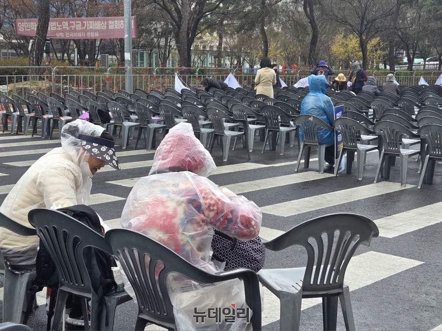 ▲ 29일 오후 서울 여의도 국회의사당 앞에서 열린 '세이브코리아' 집회에 참석한 시민들이 비옷을 입고 앉아있다. ⓒ박서아 기자