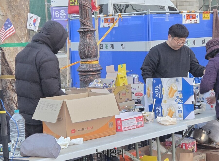 ▲ 31일 새벽 안국역 5번출구 탄핵 반대 철야 농성장 옆에서 청년 봉사자들이 시민들에게 라면과 커피를 건네고 있다. ⓒ박서아 기자