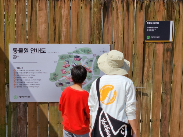 ▲ 동물원 안내도를 관찰 중인 봉사단원과 구산초 학생ⓒ교촌에프앤비
