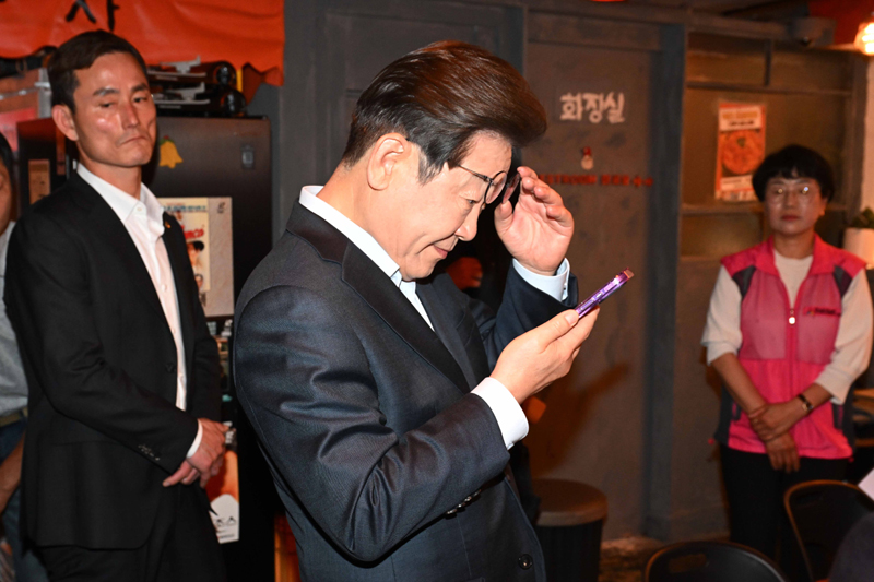 ▲ 이재명 더불어민주당 대선후보가 1일 오후 서울 종로구의 한 포장마차에서 열린 비전형 노동자 간담회를 마친 뒤 휴대전화를 확인하고 있다. 대법원 전원합의체는 이날 이 후보에게 무죄를 선고한 원심 판결을 파기하고 사건을 서울고법으로 돌려보냈다. ⓒ뉴시스