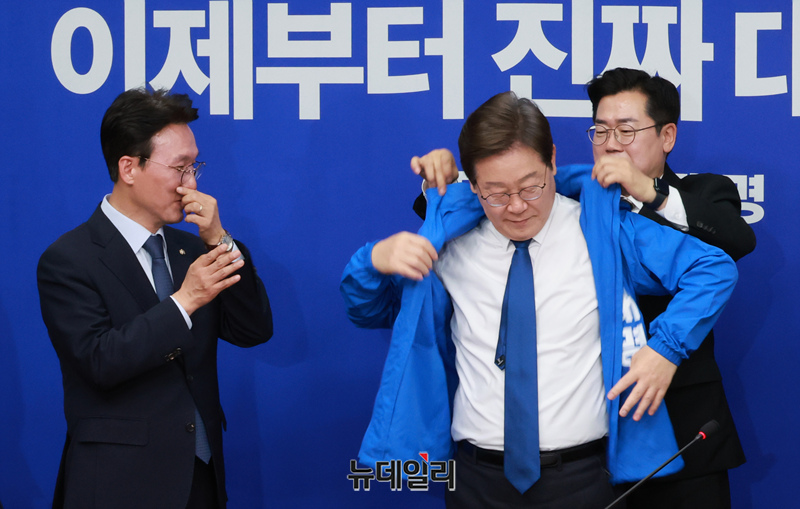 ▲ 박찬대 더불어민주당 당대표 직무대행 겸 원내대표가 28일 오전 국회에서 열린 최고위원회의에서 이재명 대선 후보에게 선거운동용 당점퍼를 입혀주고 있다. ⓒ이종현 기자