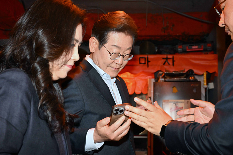 ▲ 이재명 더불어민주당 대선후보가 지난 1일 서울 종로구의 한 포장마차에서 열린 비전형 노동자 간담회를 마친 뒤 휴대전화를 확인하고 있다. 대법원 전원합의체는 이날 이 후보에게 무죄를 선고한 원심 판결을 파기하고 사건을 서울고법으로 돌려보냈다. ⓒ뉴시스