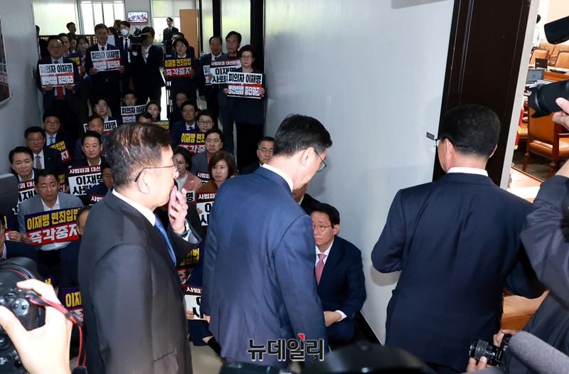 ▲ 국민의힘 의원들이 7일 오후 국회 행정안전위원회 회의실 앞 복도에서 공직선거법 개정안 의결 관련 규탄대회를 벌이는 가운데 더불어민주당 소속 신정훈 위원장이 회의실로 들어가고 있다. ⓒ이종현 기자