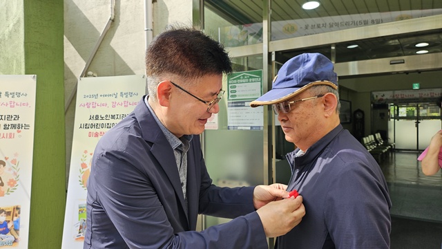 ▲ 경기 수원의 서호노인복지관 관계자가 8일 어버이날을 맞아 복지관 이용 노인에게 '사랑의 꽃핀(뜨개꽃 브로치) 달아드리기' 행사를 진행하고 있다. ⓒ서호노인복지관 제공