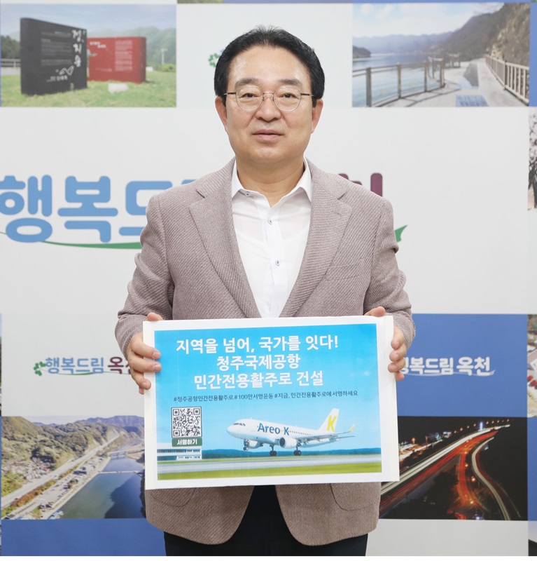 ▲ 옥천군 황규철 군수가 ‘지역을넘어, 국가를 잇다! 청주국제공항 민간전용활주로 건설’이라는 표어가 적힌 팻말을 들고 릴레이 캠페인에 참여하고 있다. ⓒ옥천군