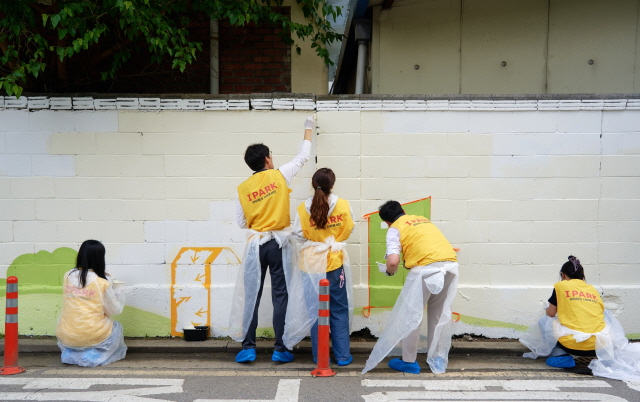 ▲ HDC현대산업개발 직원들이 지난 15일 서울 용산구에서 용강중 담장 벽화를 그리고 있다.ⓒHDC현대산업개발