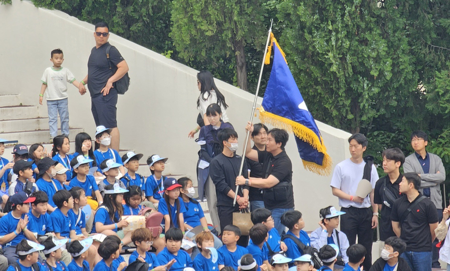 ▲ 17일 열린 '2025학년도 대구경북본부 합동 선서식'에서 한 교사가 단가에 맞춰 학교 깃발을 흔들며 입장하고 있다.ⓒ한국과학우주청소년단