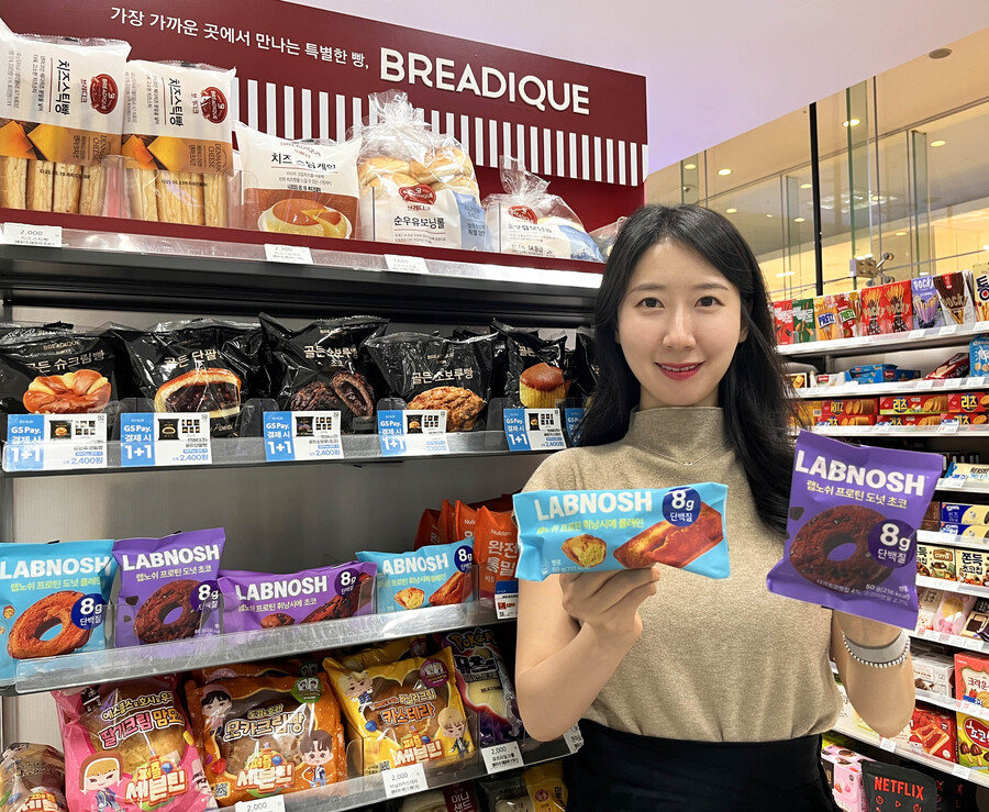 ▲ GS25에서 모델이 랩노쉬 프로틴 휘낭시에 플레인, 랩노쉬 프로틴 도넛 초코를 들고 포즈를 취하고 있다.ⓒGS25