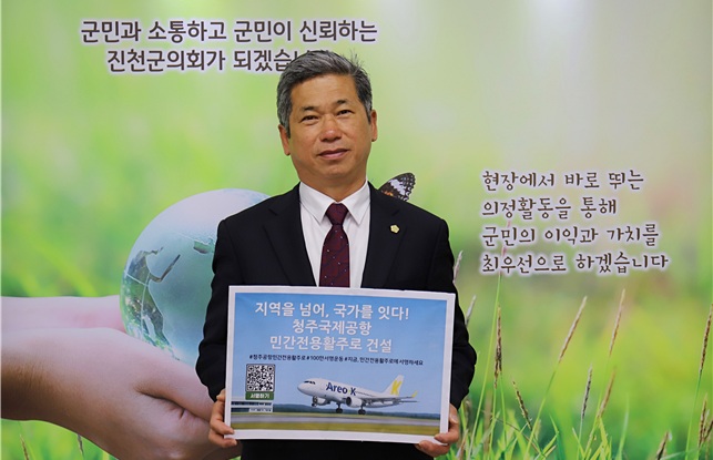 ▲ 이재명 진천군의회 의장이 ‘청주공항 민간 전용 활주로 건설, 서명운동 동참’이라는 표어를 들고 릴레이 캠페인에 참여했다.ⓒ진천군