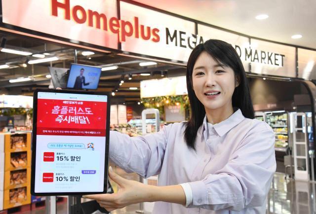 ▲ 모델이 서울 등촌동 홈플러스 메가 푸드 마켓 라이브 강서점에서 배달의민족과 함께 선보인 대형마트 퀵커머스 서비스를 소개하고 있다. ⓒ홈플러스